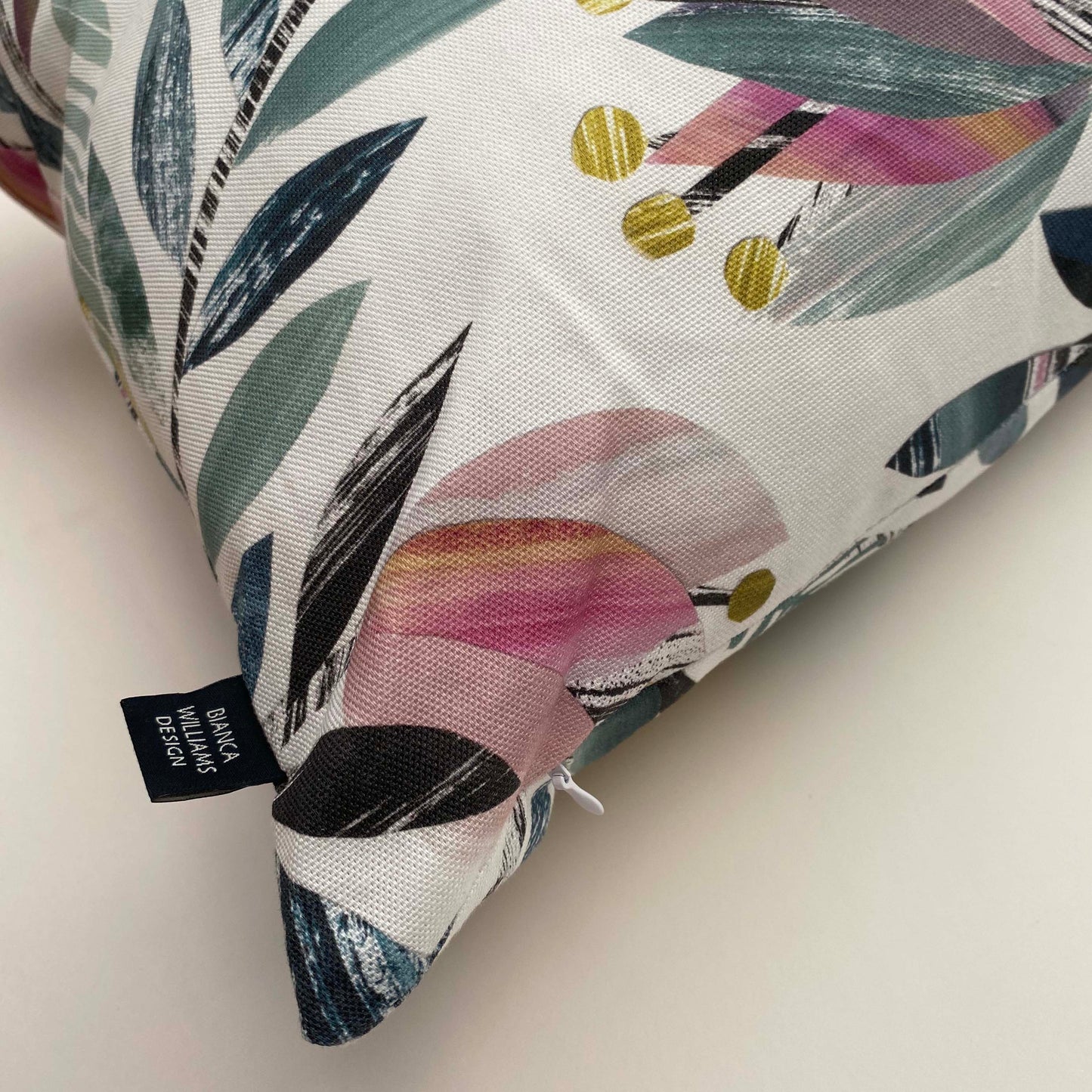 A close up of the corner of the Tulip Cushion, showing the concealed zip and Bianca Williams Design Brand Label sewn into the edges.