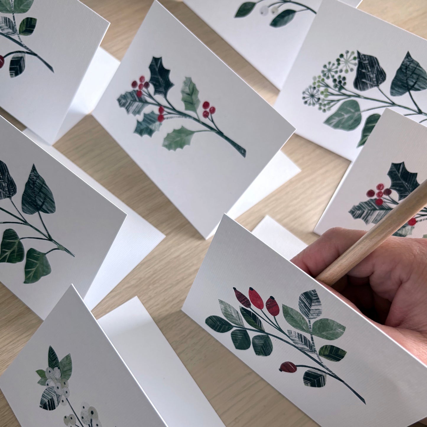 The Winter Floral Mini cards have been placed on a wooden surface.  You can see a hand writing into one of the cards.