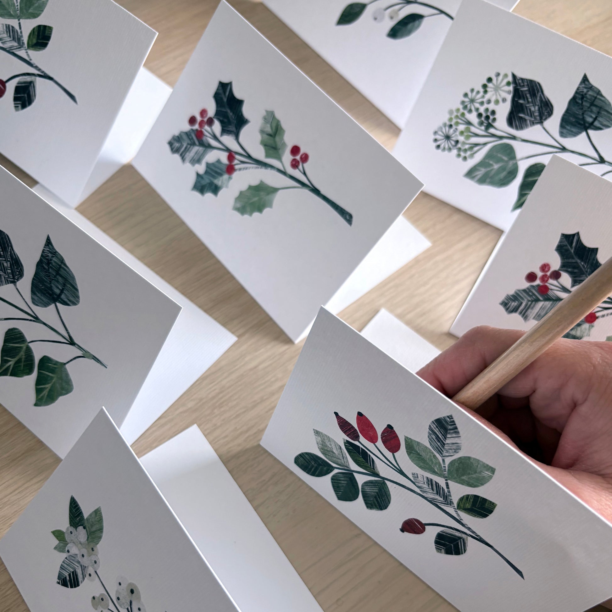 The Winter Floral Mini cards have been placed on a wooden surface.  You can see a hand writing into one of the cards.