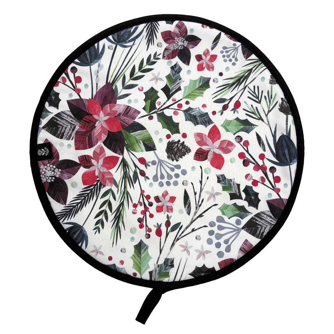 A round Aga Cover with a black trim and hanging loop, features a colourful winter botanical pattern of poinsettias, holly leaves, pinecones, and berries, shown on a white background.