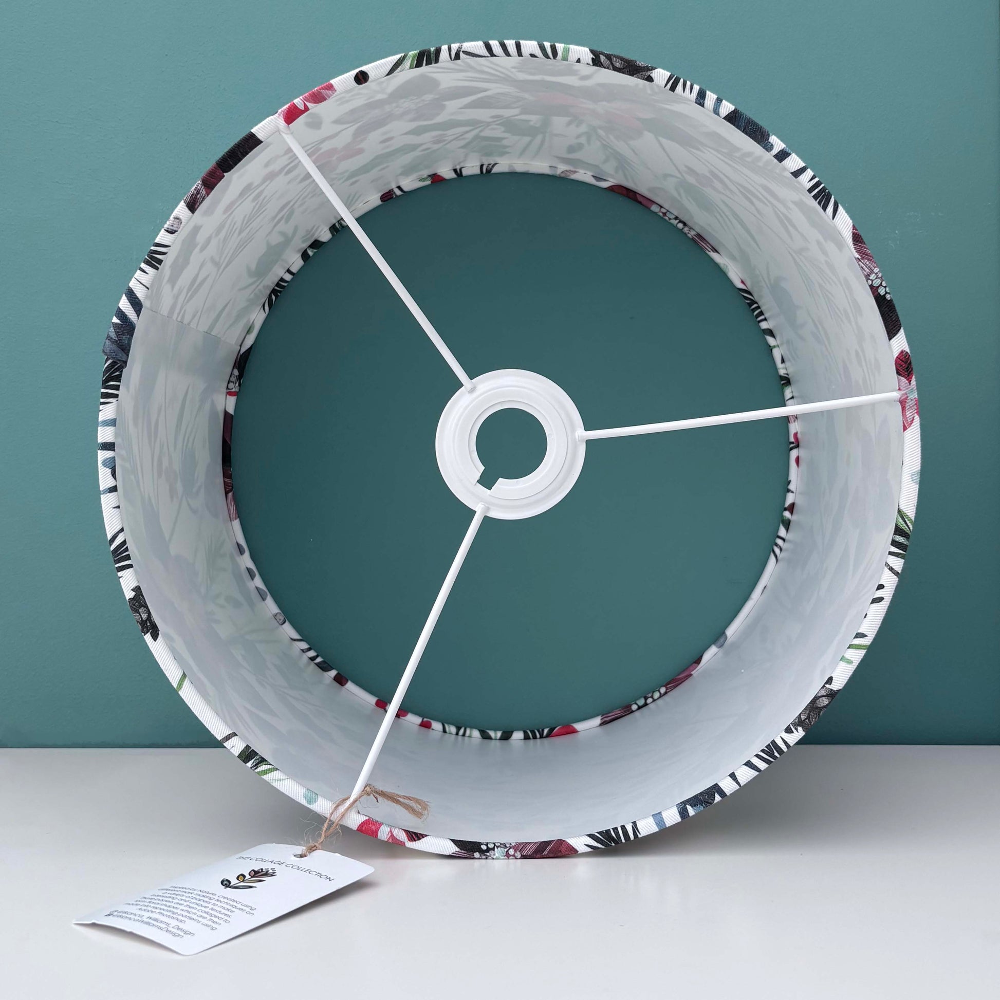 Inside a Winter Floral patterned lampshade.  It has been placed on a white shelf against a blue green background.