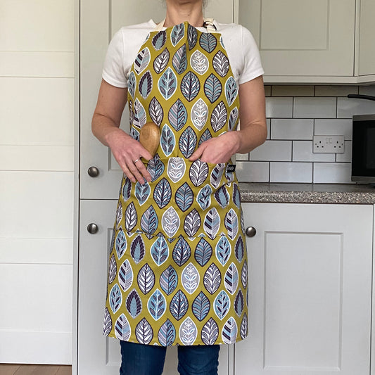 Model wears Yellow Scandinavian style leaf print Apron. With double pockets to the front and an adjustable ecru neck strap.