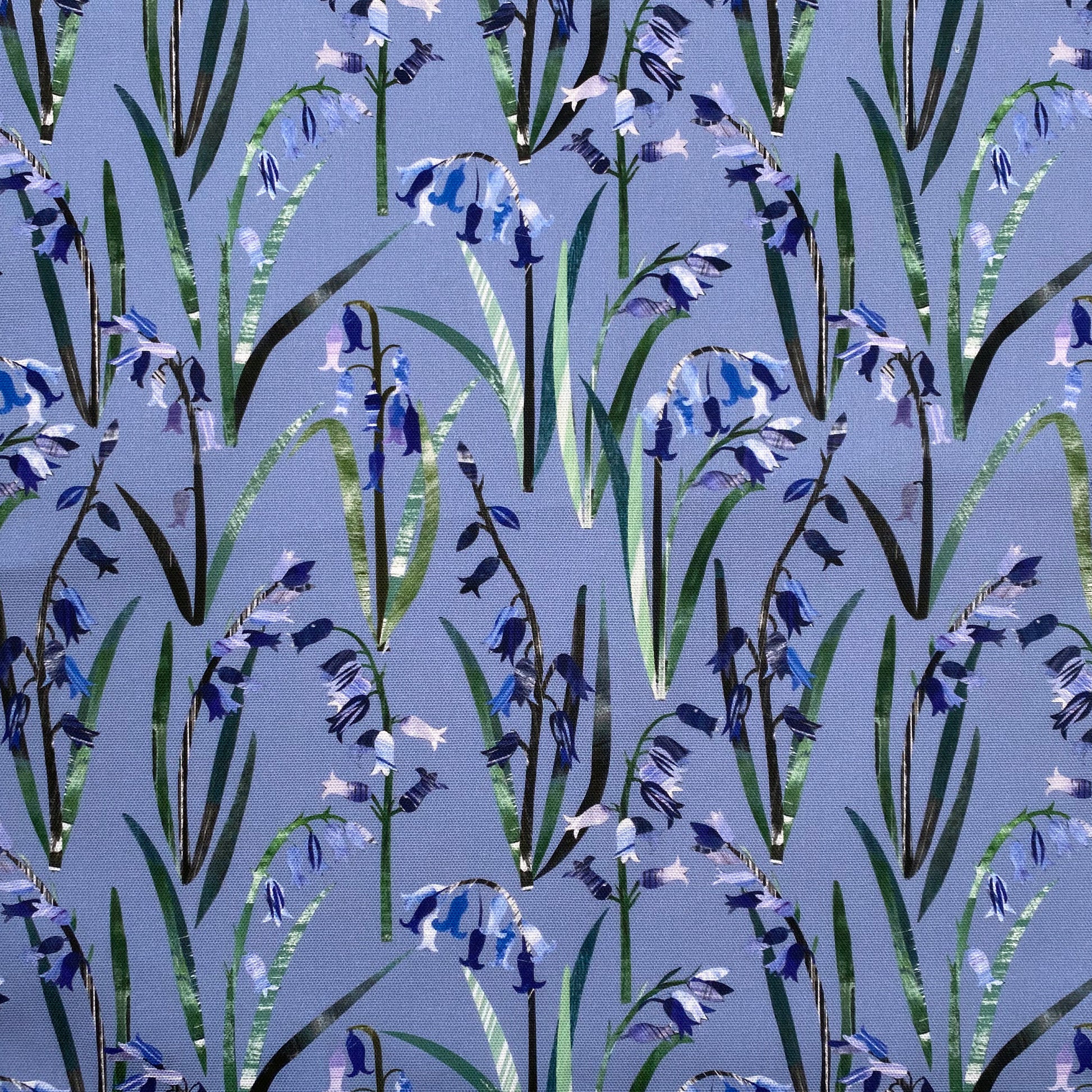 Blue textured Bluebells with green leaves have been printed onto a Blue cotton background.