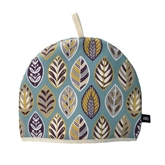 A Blue Leaf Tea Cosy has been placed on a white background, a brand label has been sewn into the outside seam and you can also see the grab loop at the top.