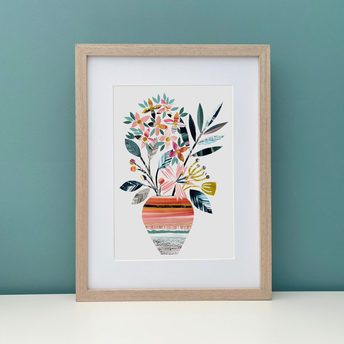 Framed artwork of a colorful floral design on a teal wall.