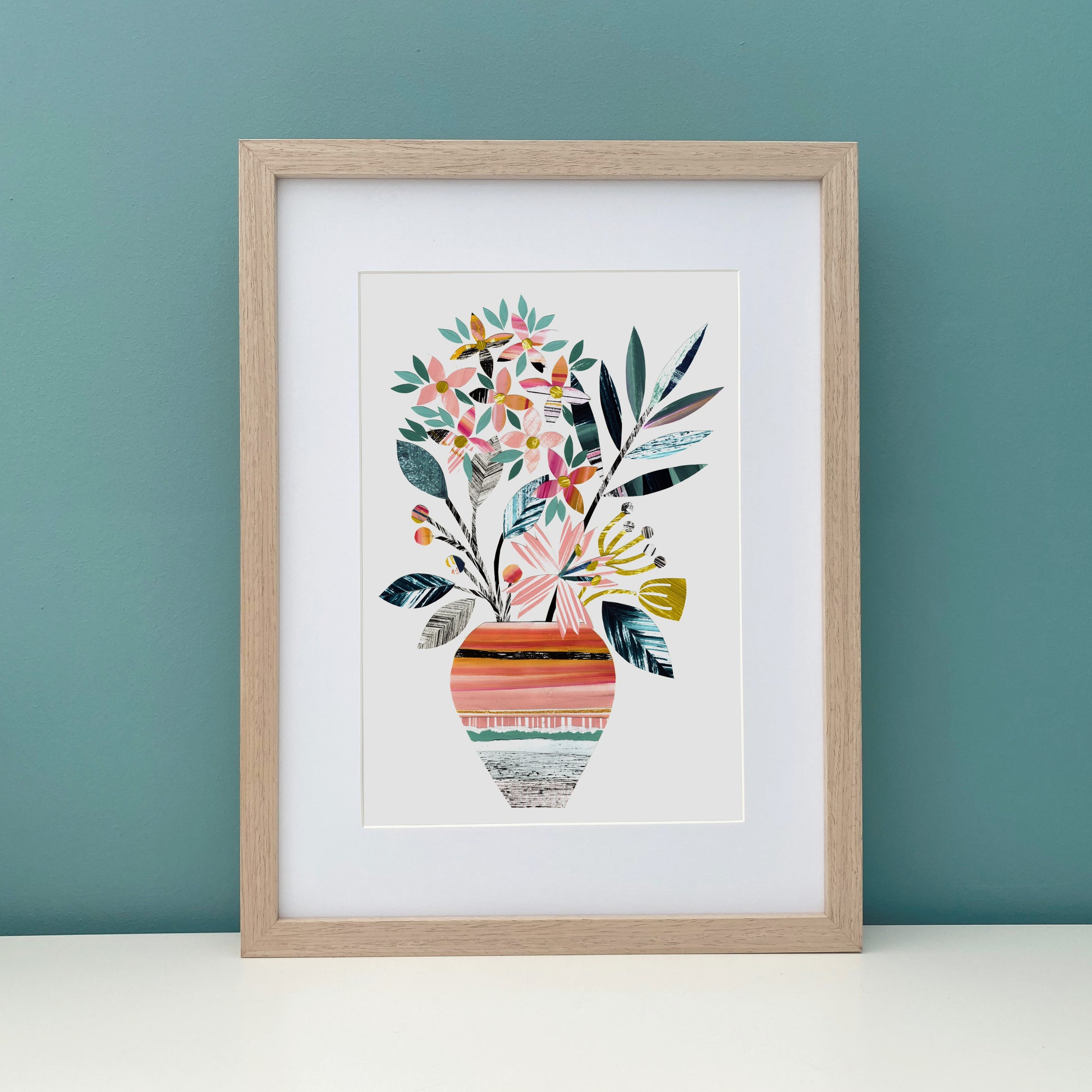 Framed artwork of a colorful floral design on a teal wall.