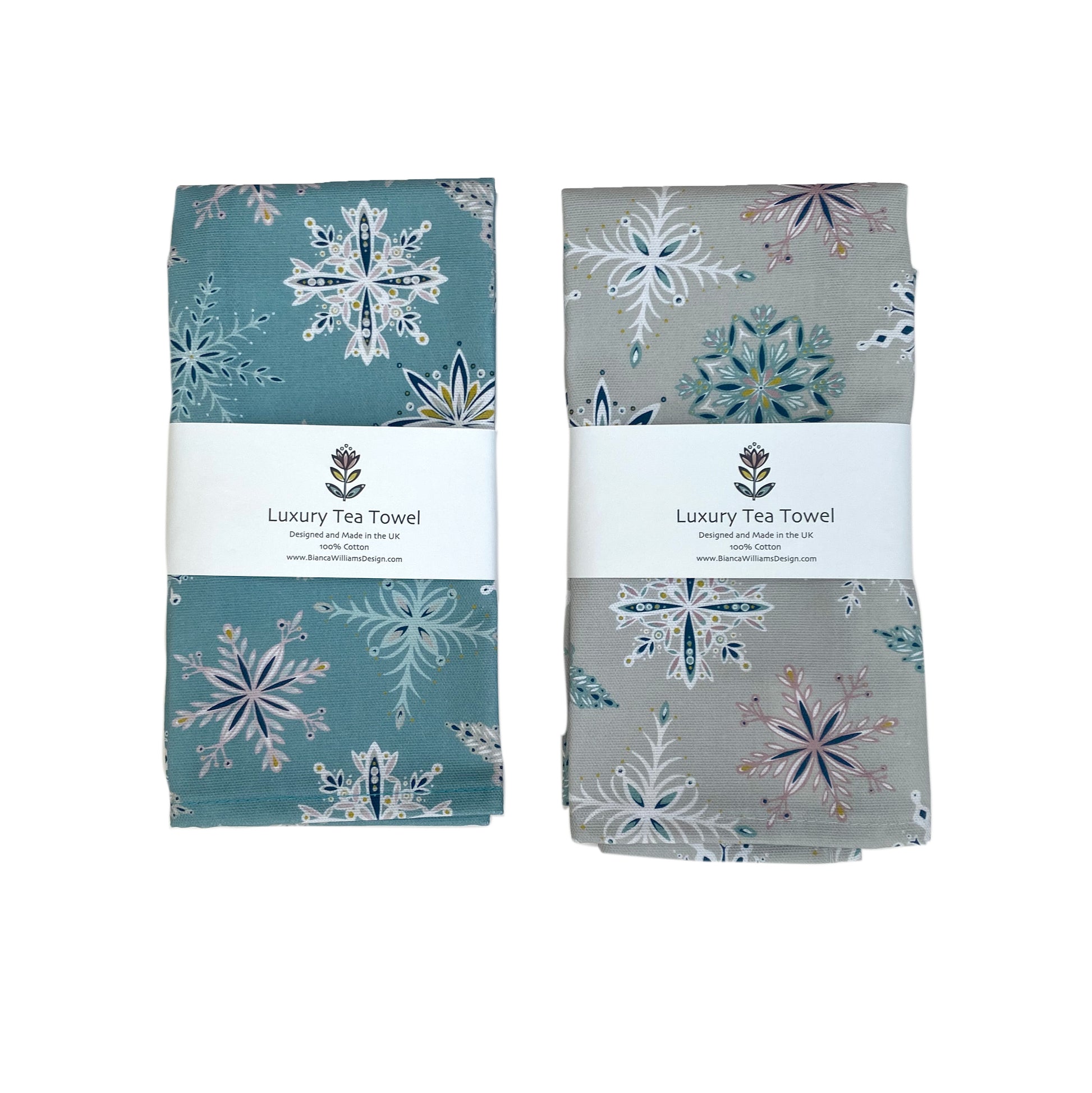 One Blue and one Grey Snowflake Tea Towel have been packaged in a branded belly band and placed on a white background.