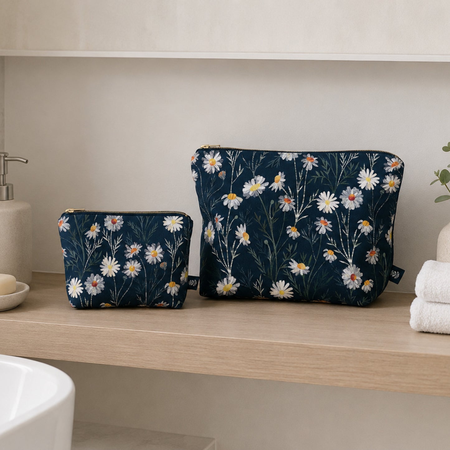 Two Daisy floral-patterned pouches on a bathroom counter with a neutral background
