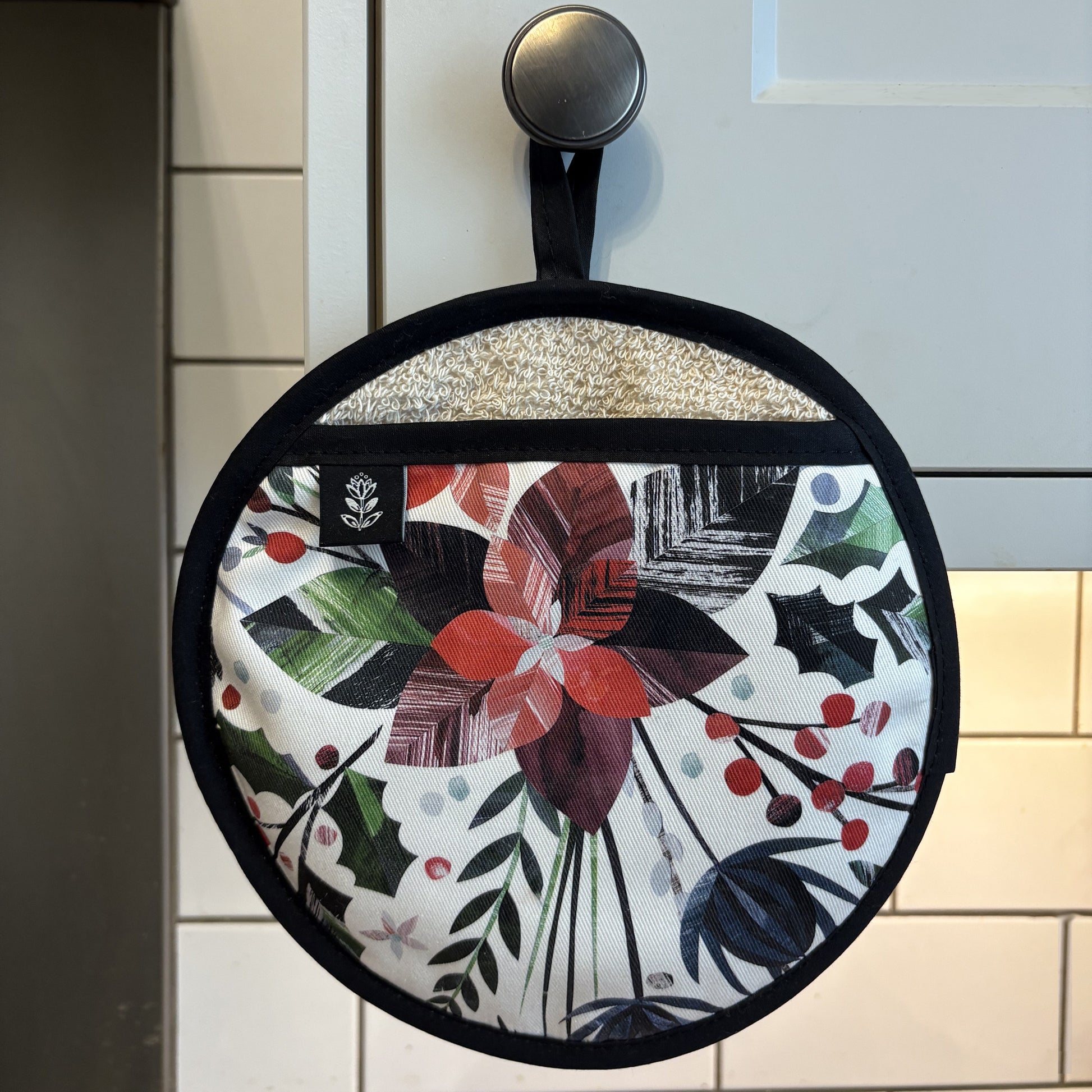 Winter Floral pot grab is hanging on a grey kitchen door handle.